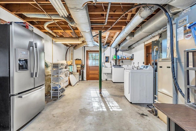 basement featuring stainless steel fridge with ice dispenser, sink, and washer and dryer