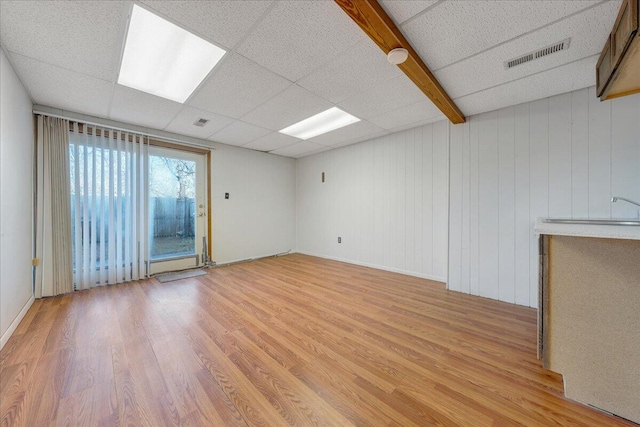 unfurnished room with a drop ceiling, sink, and light hardwood / wood-style flooring