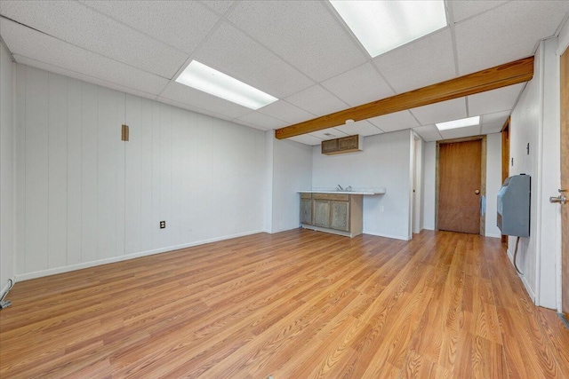 unfurnished living room featuring a paneled ceiling and light wood-type flooring