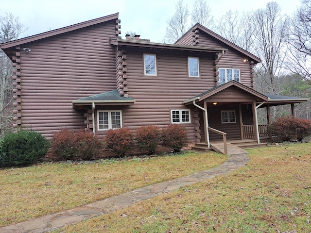 cabin with covered porch, a front lawn, and log siding