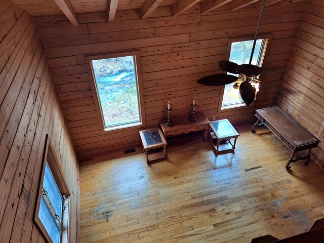 spare room with light wood-style floors, baseboards, and beamed ceiling