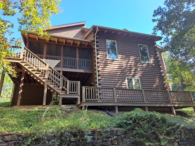 rear view of property featuring a sunroom, stairs, and log siding