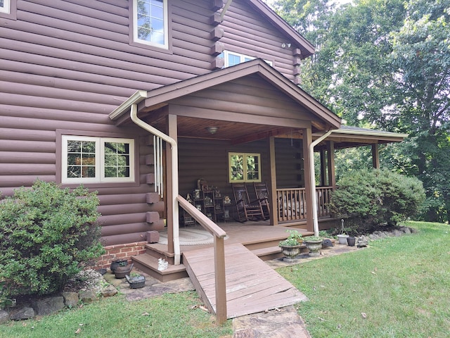 entrance to property featuring log exterior, a lawn, and a wooden deck