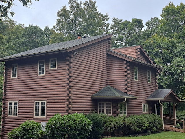 view of property exterior featuring log exterior and roof with shingles