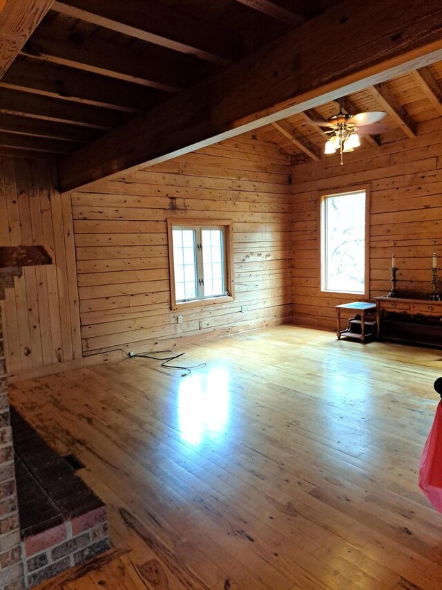 unfurnished living room featuring wood walls, a brick fireplace, wood finished floors, and a notable chandelier