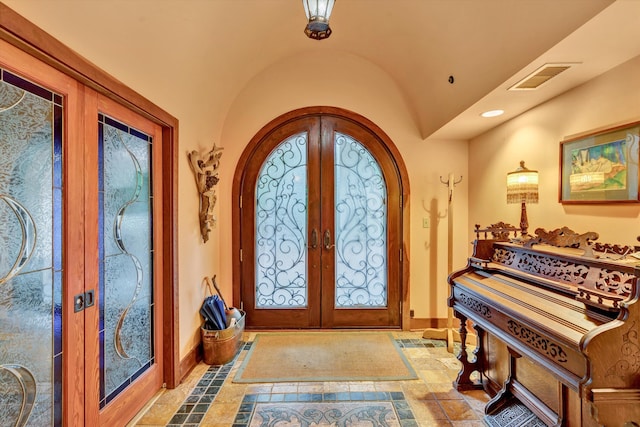 tiled entryway featuring french doors and vaulted ceiling