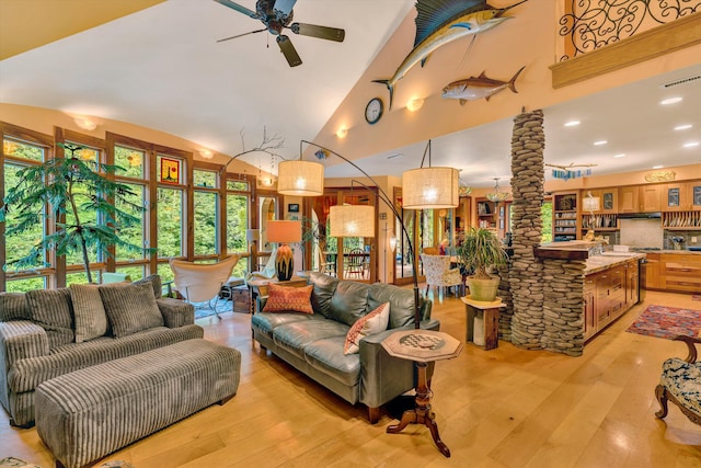 living room with ornate columns, ceiling fan, high vaulted ceiling, and light hardwood / wood-style floors