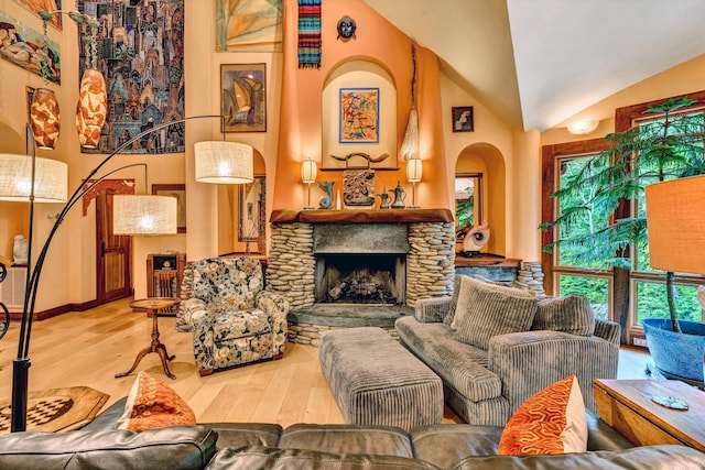 living room featuring light wood-type flooring, a stone fireplace, and lofted ceiling