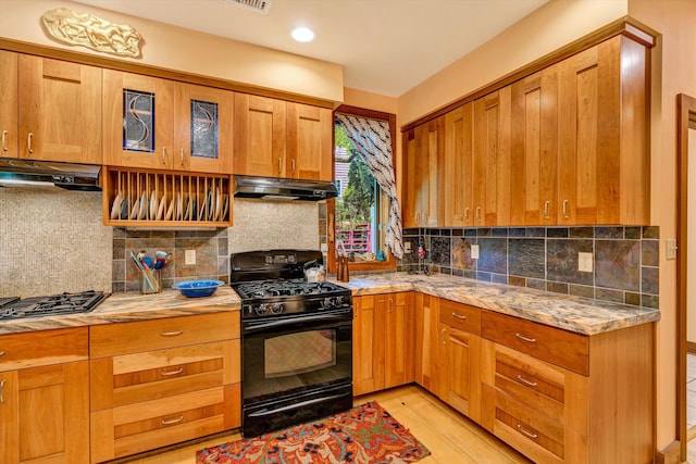 kitchen featuring ventilation hood, black gas range, and decorative backsplash