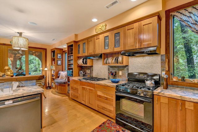 kitchen with appliances with stainless steel finishes, backsplash, light hardwood / wood-style floors, and a wealth of natural light