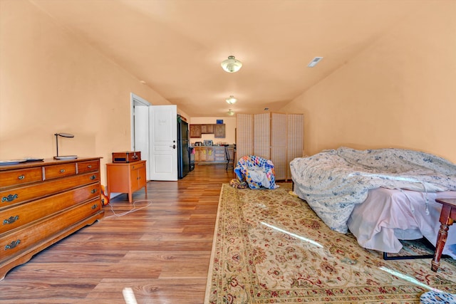 bedroom featuring black refrigerator and light hardwood / wood-style floors