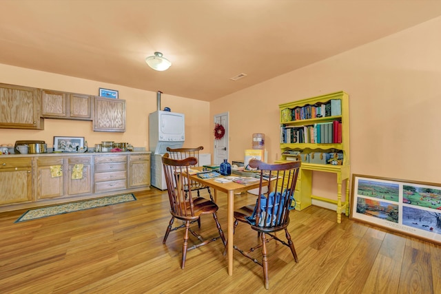 dining room featuring light wood-type flooring and stacked washing maching and dryer