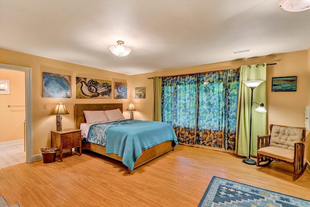 bedroom featuring wood-type flooring and ensuite bath