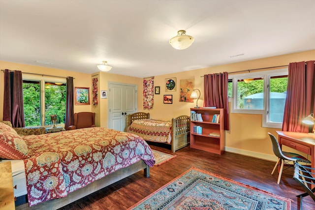 bedroom with multiple windows and dark wood-type flooring