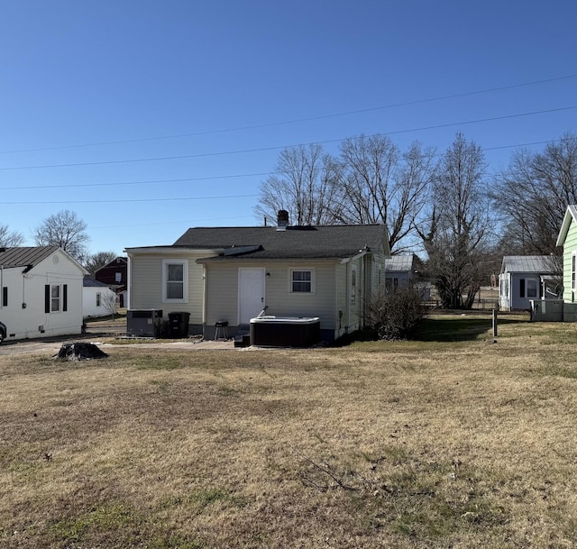 rear view of house with central air condition unit and a lawn