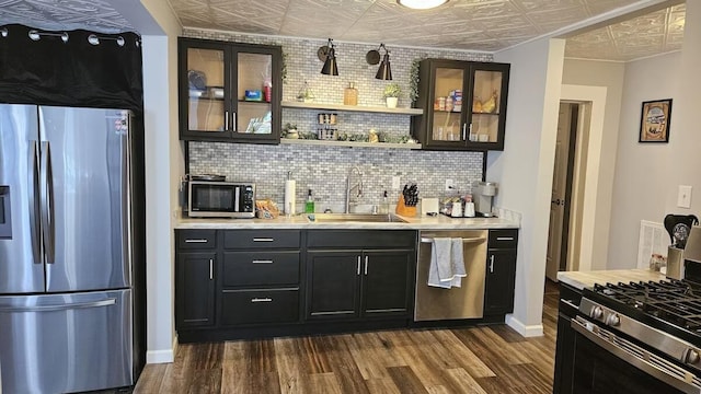 bar with appliances with stainless steel finishes, tasteful backsplash, dark wood-type flooring, and sink