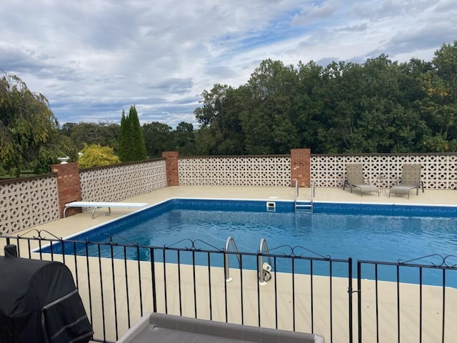 view of swimming pool with a diving board and grilling area