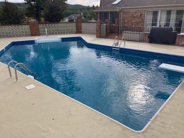 view of swimming pool featuring a diving board and a patio