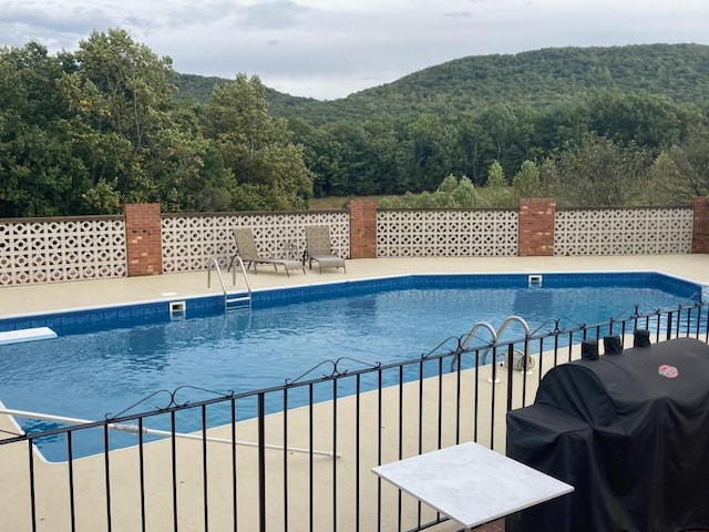 view of swimming pool featuring a mountain view, a patio, and grilling area