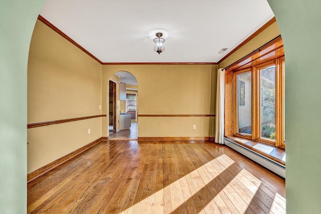 spare room with wood-type flooring, ornamental molding, and a baseboard heating unit