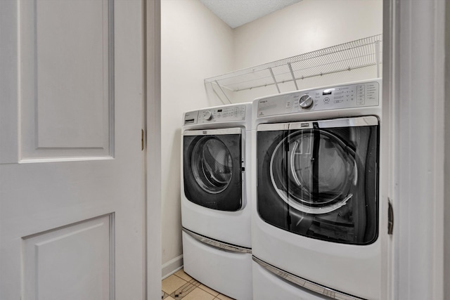 washroom featuring washing machine and dryer, light tile patterned flooring, and a textured ceiling