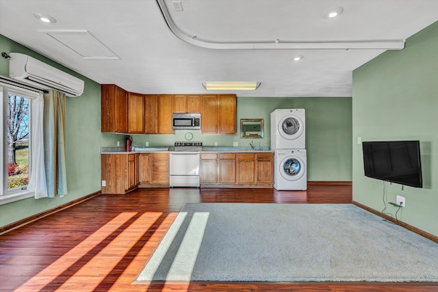 kitchen featuring a wall unit AC, stove, dark wood-type flooring, and stacked washer and clothes dryer