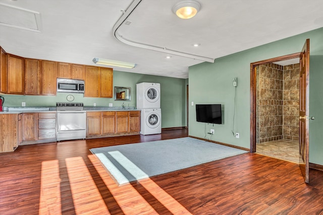 kitchen featuring stove, dark hardwood / wood-style flooring, stacked washer and dryer, and sink