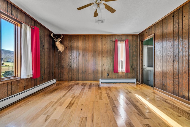 empty room with wood walls and a baseboard heating unit