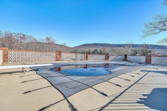 view of pool featuring a mountain view, a patio, and a diving board