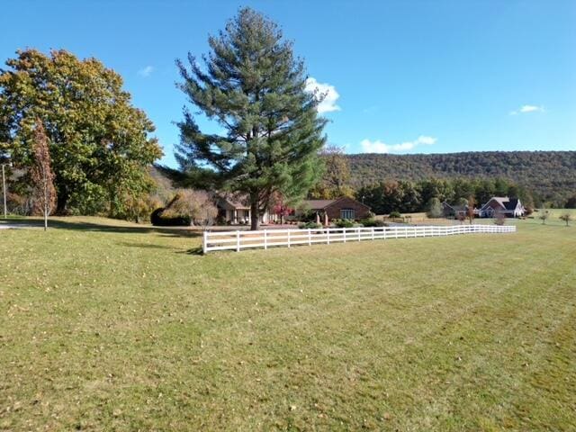 view of yard with fence and a rural view