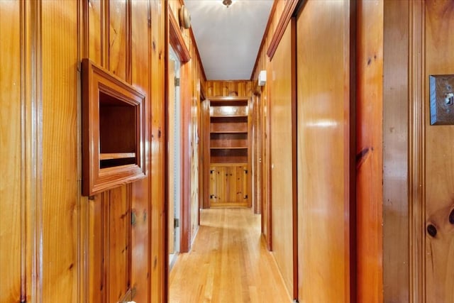 corridor featuring light wood-type flooring and wood walls