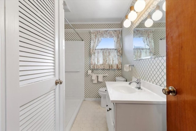 bathroom featuring tiled shower, vanity, and toilet