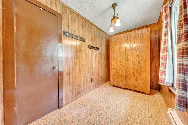 spare room featuring wood walls, crown molding, a baseboard radiator, and a textured ceiling