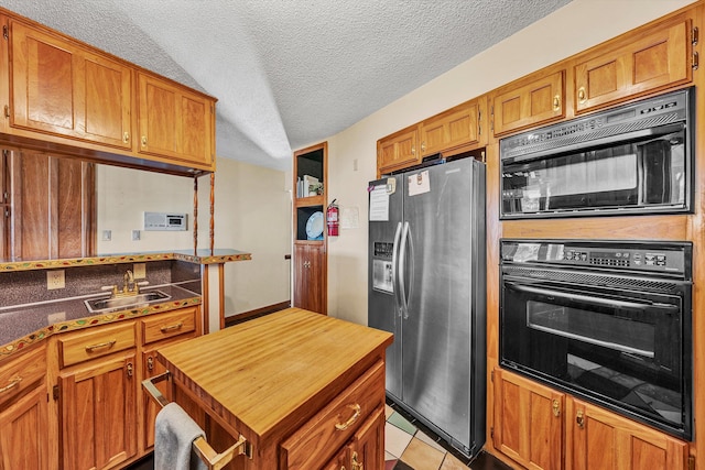 kitchen featuring sink, light tile patterned floors, a textured ceiling, and black appliances