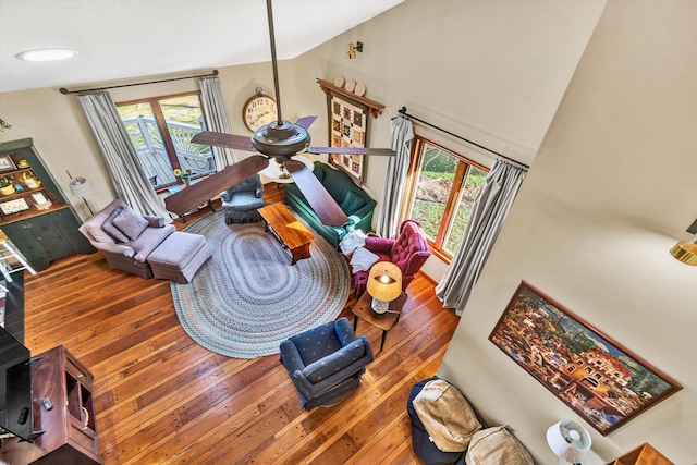 living room with a wealth of natural light, high vaulted ceiling, and wood-type flooring