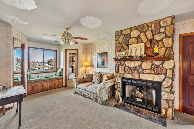 carpeted living room featuring ceiling fan and a stone fireplace