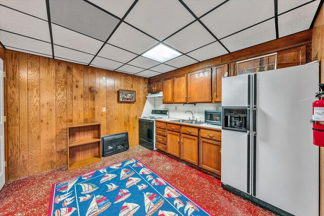 kitchen featuring sink, a drop ceiling, wood walls, and black appliances