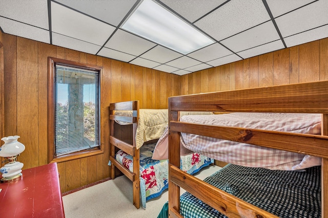 bedroom with wood walls, a drop ceiling, and carpet floors