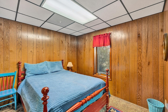 bedroom with a drop ceiling and wooden walls