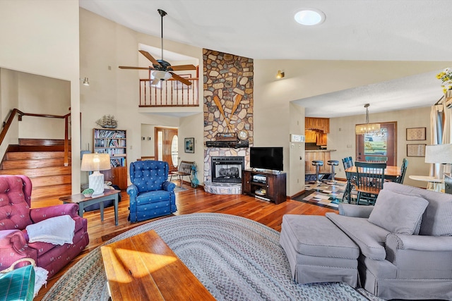 living room with ceiling fan, wood-type flooring, a fireplace, and high vaulted ceiling