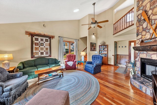 living room with ceiling fan, a fireplace, high vaulted ceiling, and light hardwood / wood-style floors