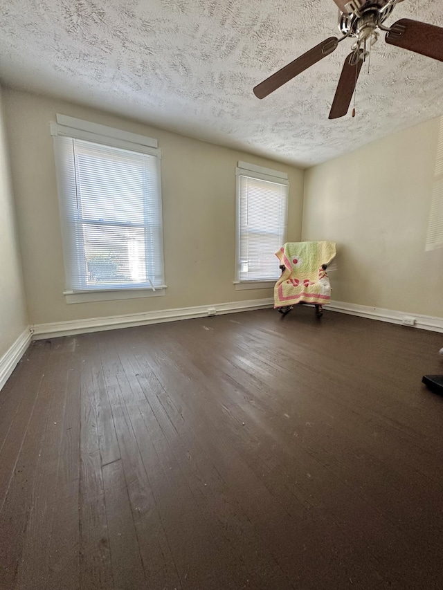 spare room featuring a textured ceiling, dark hardwood / wood-style floors, and a wealth of natural light