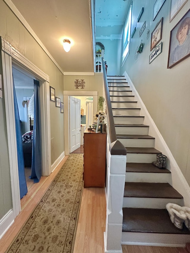 staircase featuring hardwood / wood-style floors and crown molding