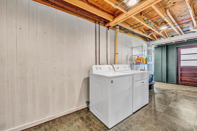 clothes washing area featuring wooden walls and washer and dryer