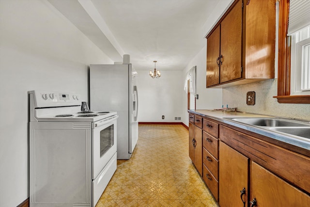 kitchen featuring pendant lighting, white appliances, sink, and an inviting chandelier