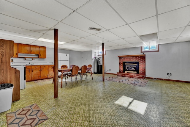 dining space featuring a paneled ceiling, a brick fireplace, and water heater