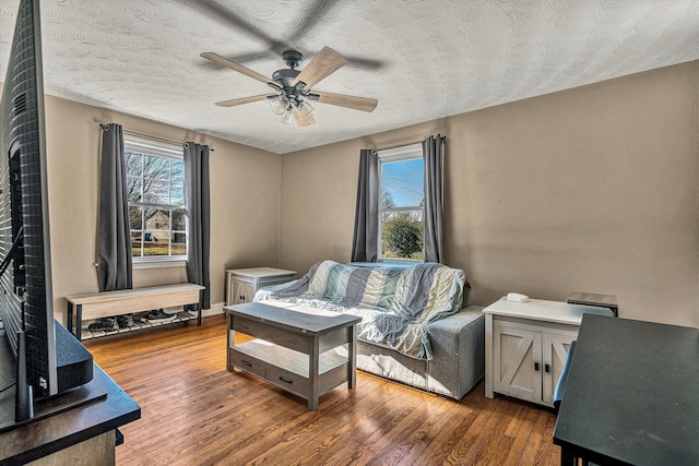 living area with a textured ceiling, ceiling fan, and dark hardwood / wood-style floors