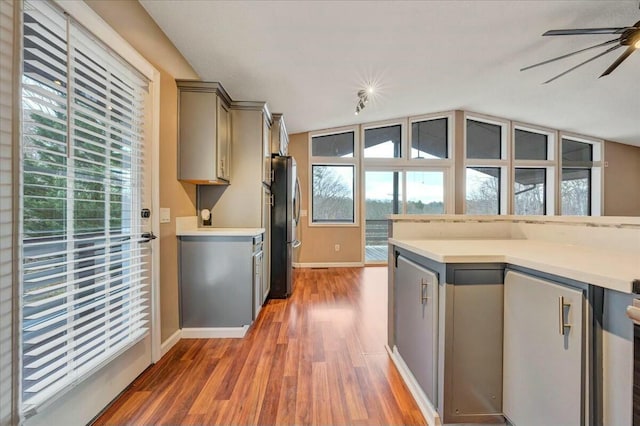 kitchen featuring gray cabinets, light countertops, dark wood-type flooring, freestanding refrigerator, and ceiling fan