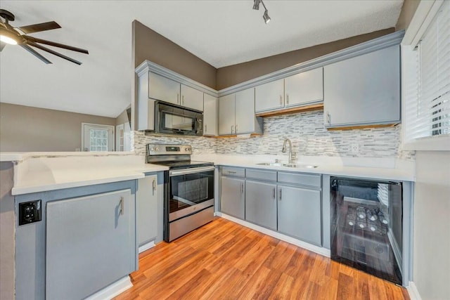 kitchen featuring black microwave, wine cooler, a sink, light countertops, and stainless steel electric range oven