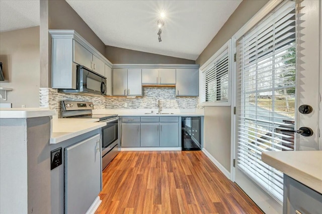 kitchen with gray cabinets, light countertops, vaulted ceiling, and black appliances